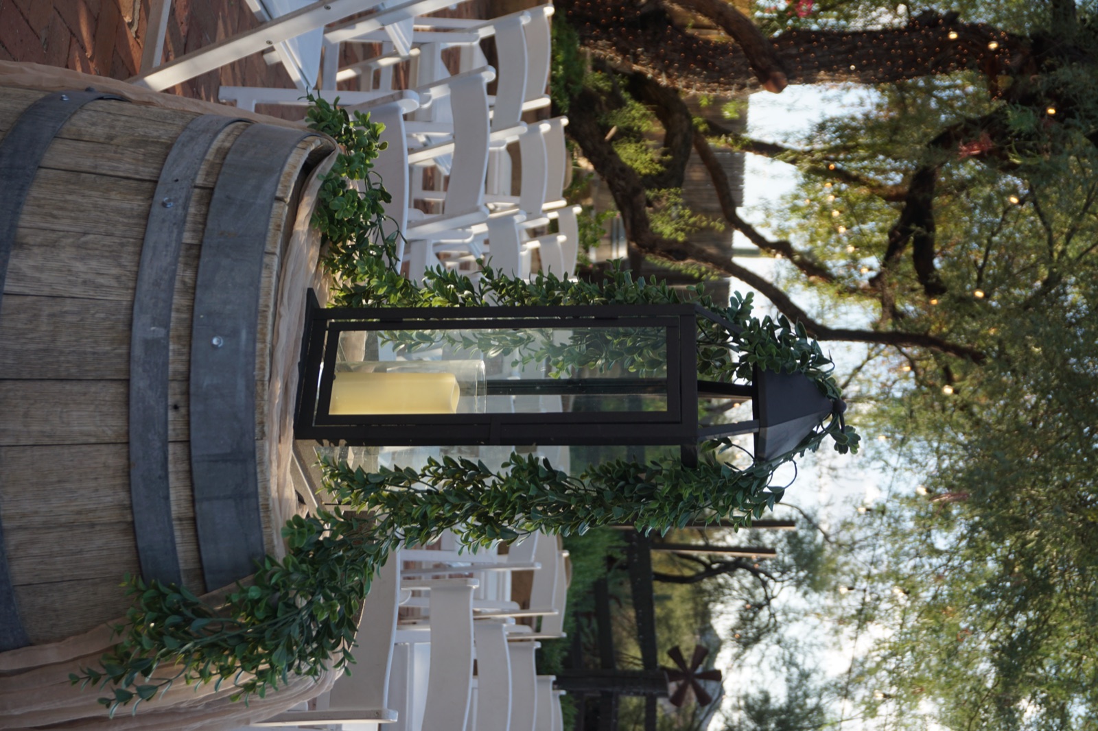 Candle lantern and greenery on a wine barrel at a wedding ceremony